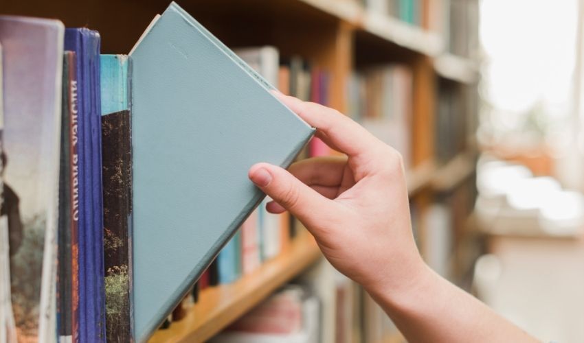 Desafios para a prática da leitura no Brasil: imagem de uma pessoa pegando um livro na biblioteca